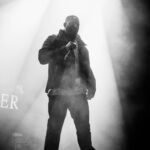 Dynamic black and white image of a rapper performing live onstage with striking lights.